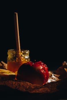 Honey with wooden honey dipper and fruits on wooden table close up