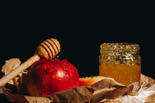 Honey with wooden honey dipper and fruits on wooden table close up