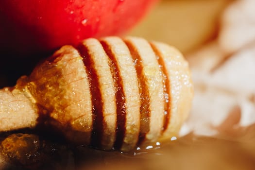 Honey with wooden honey dipper and fruits on wooden table close up