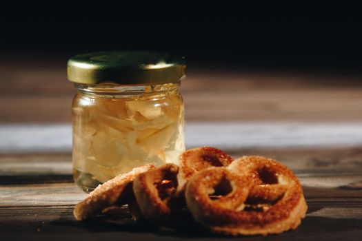 jar of honey with bagels on wooden table close up with honey dipper on black background