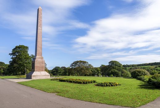 Magnificent McGrigor Obelisk with flower beds in front on a blue sky background, Duthie Park, Aberdeen, Scotland