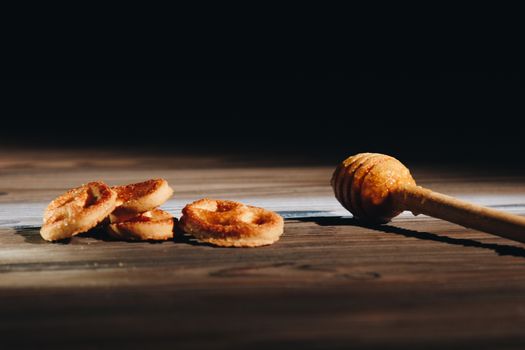 jar of honey with bagels on wooden table close up with honey dipper on black background