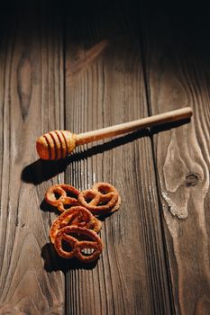 jar of honey with bagels on wooden table close up with honey dipper on black background