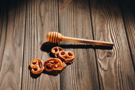 jar of honey with bagels on wooden table close up with honey dipper on black background