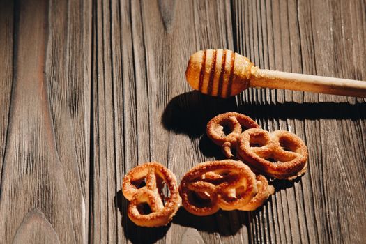 jar of honey with bagels on wooden table close up with honey dipper on black background