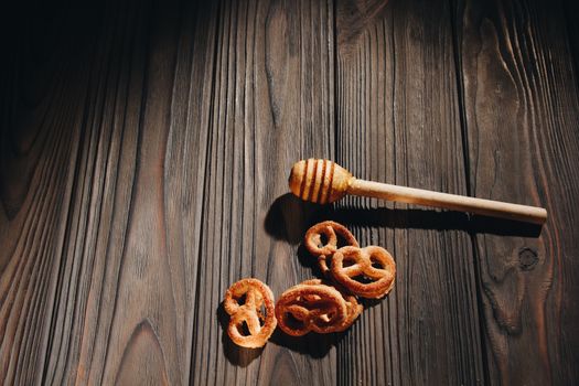 jar of honey with bagels on wooden table close up with honey dipper on black background