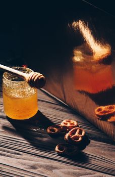 jar of honey with bagels on wooden table close up with honey dipper on black background