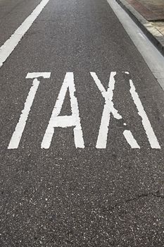 Taxi sign on the road, detail of a text signal in soil, urban transport