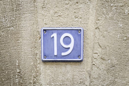 Number nineteen, detail of a metal plate with the number deiecinueve, citrate and text, signal