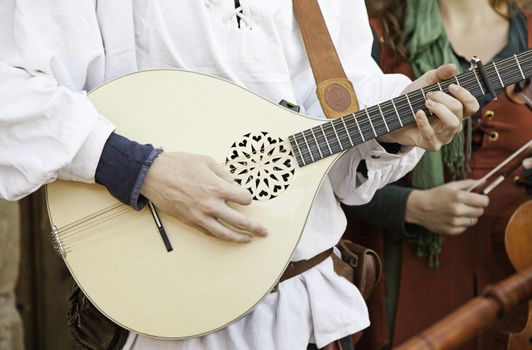 medieval guitarist, detail of an old musician playing medieval music, street show