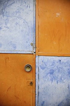 Orange and blue closed door, detail of a decorated door in the city, loneliness and abandonment