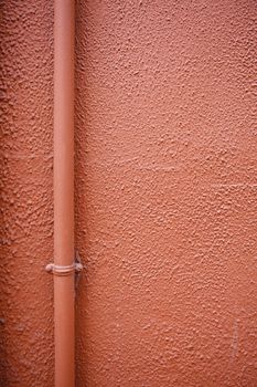 Red wall with pipe, detail of a wall of a building in the city, textured background