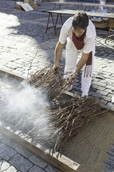 Person roasting on a grill, detail of a man cooking meat on a charcoal fire