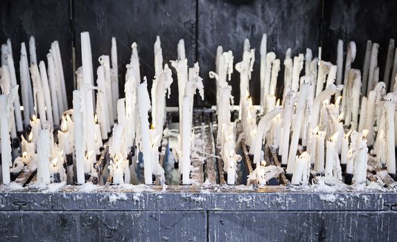 Burning candles in a church, detail of lighted wax candles to pray Christian tradition, faith