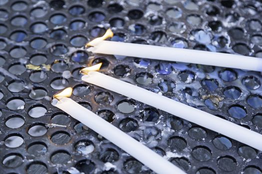 Wax candles elongated, detail of blue candles lit, belief and religion