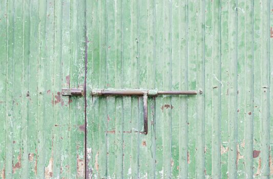 Green metal door, detail of a closed door painted green, safety and security