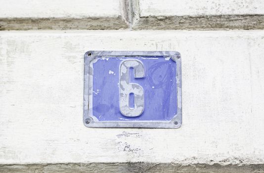 Wall with number six, detail of a wall with a plate with a number, information and indication