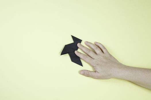 Bow tie on the wall, paper art detail, man's hand on the wall, origami