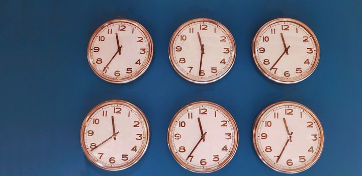 Six wall clocks with twelve hour clock face on blue background