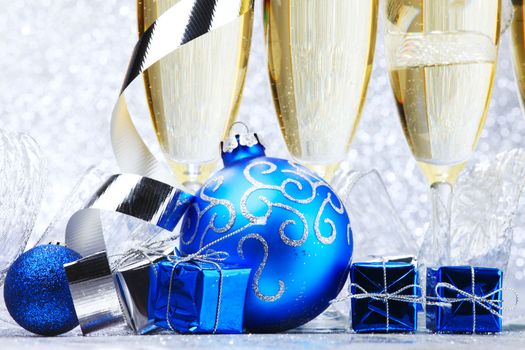 Glasses of champagne and decorative christmas balls on glitter background
