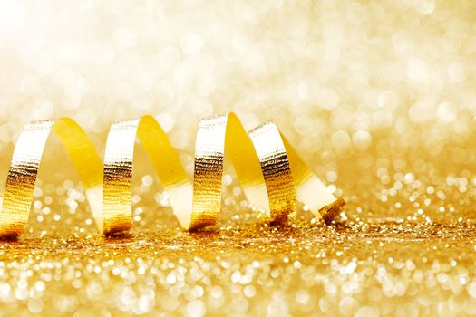 Golden curly ribbon decoration on glitter background close-up