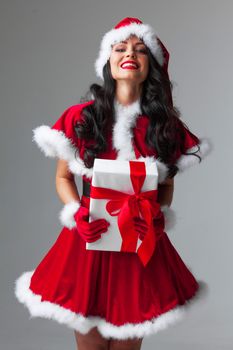 Woman in red Santa Claus outfit holding christmas gift box