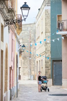 Presicce, Apulia, Italy - A woman wheeling her stroller through the old town