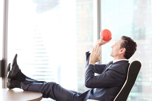 Business man playing with a basketball at the office