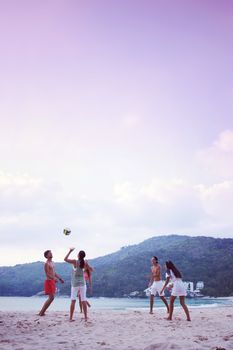 Group of young people playing volleyball at beach