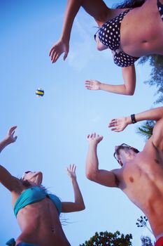 Group of young people playing volleyball outdoors