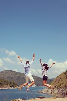 Young couple jumping, beautiful sea view on background