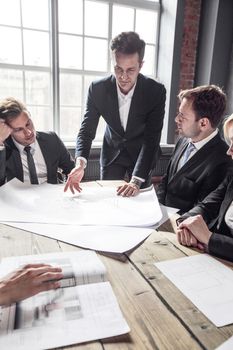 Business people discuss construction blueprint on office table