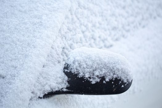 Snow overnight blanketed the landscape, including the roads and cars. A close up of a front car and side mirror