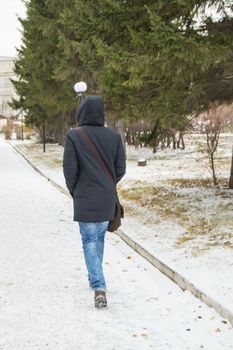 young man in a jacket with a hood quickly rides on a snow-covered road to the winter Park
