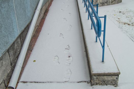 Footprints in the snow on the ramp installed for the movement of people with disabilities at any time of the year.