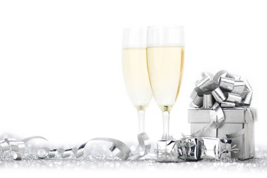 Two elegant flutes of sparkling champagne with decorative silver gifts