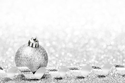 Christmas ball and curly decorative ribbon on bokeh background