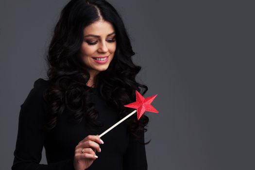 Woman with star shaped magic wand on gray background with copy space