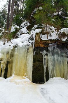 Frozen waterfalls on the rock, orange colored and snow