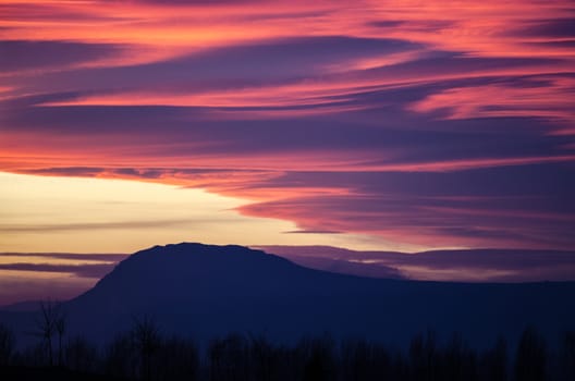 Orange and purple fluffy clouds at sunset over Etxauri s peak at Navarra, Spain