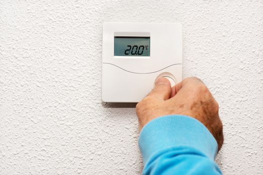 Man hand adjusting thermostat at home. Celsius temperature scale.