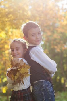 Boy and girl in school uniform with maple yellow leaves
