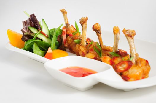 fried chilli chicken wings with vegetable salad and hot sauce