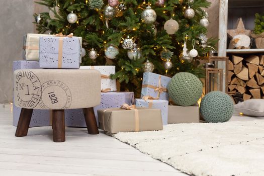 Gift boxes wrapped around the Christmas tree on the background. Cozy house is decorated to celebrate the New year.