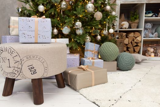 Gift boxes wrapped around the Christmas tree on the background. Cozy house is decorated to celebrate the New year.