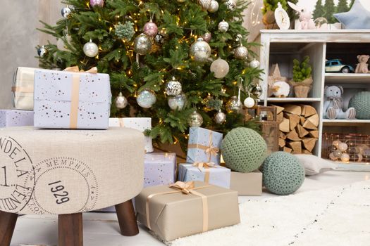 Gift boxes wrapped around the Christmas tree on the background. Cozy house is decorated to celebrate the New year.