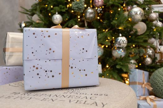 Gift boxes wrapped around the Christmas tree on the background. Cozy house is decorated to celebrate the New year.