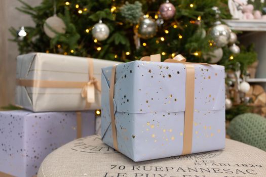 Gift boxes wrapped around the Christmas tree on the background. Cozy house is decorated to celebrate the New year.