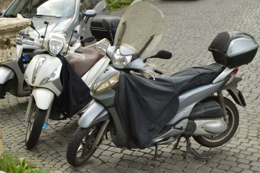 Two black motorcycles are parked on the street in Rome, Italy.