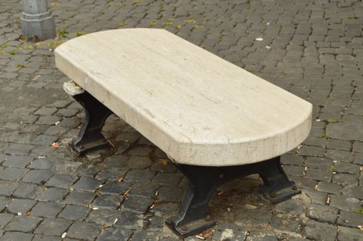 Wooden bench on the cobblestone in the tourist center of Rome, cigarette butts and garbage, cleaning problems.